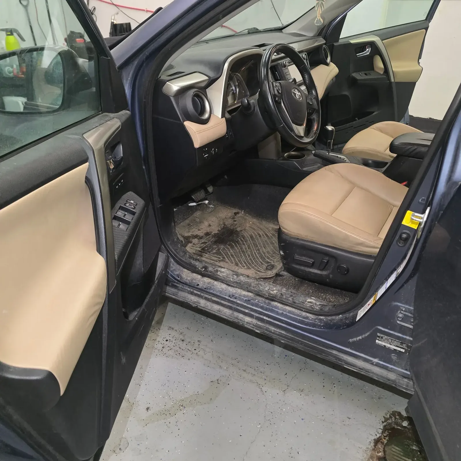 Toyota RAV4 driver area with dirty floor mat and soiled door sill before interior detailing in Anchorage, Alaska