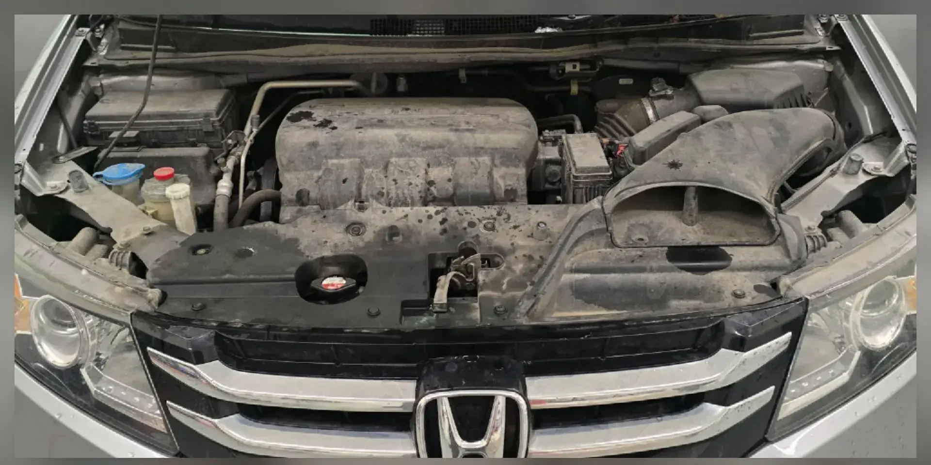 Honda Passport engine bay covered in dust and grease before engine bay cleaning in Anchorage, Alaska